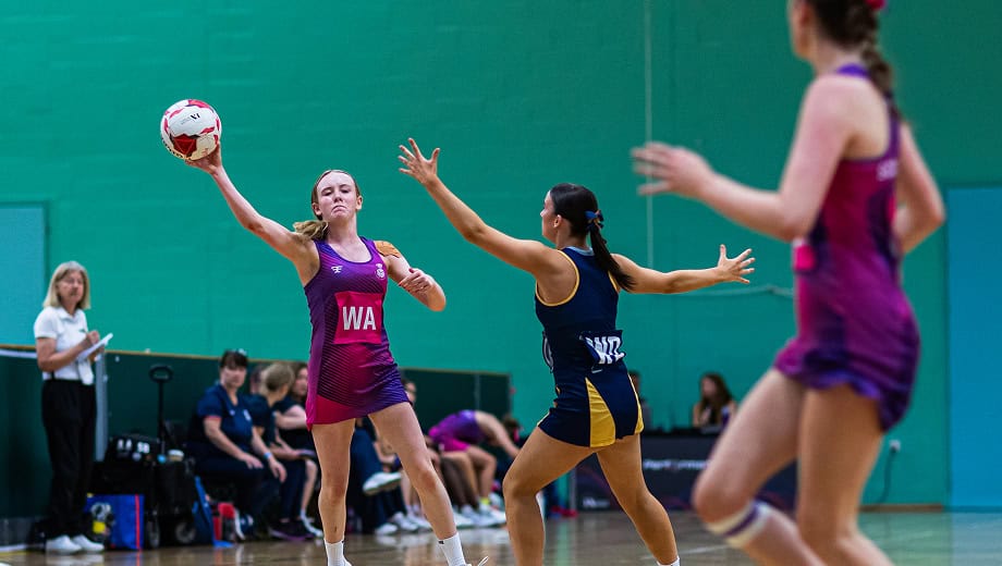Netball play attempts to pass to a team mate while an opposition player tries to intercept the pass