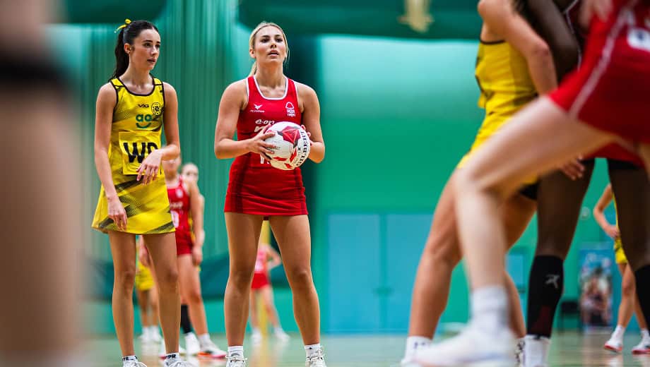 A player holding the ball looking calm while she looks for a team mate to pass too.