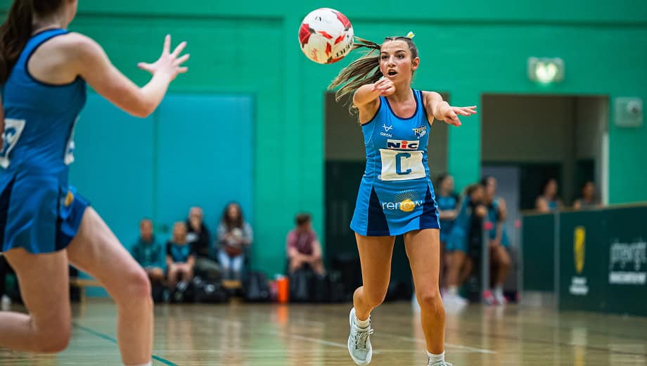 A player has just executed a pass the ball is in mid air and heading to a team mate.