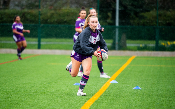 Woman running with rugby ball