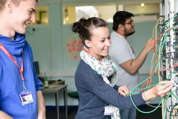 Computing students pluginig network cables into a network switch