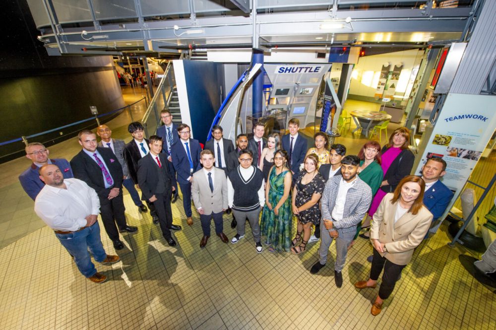 Students stood in a semi-circle next to a rocket at the National Space Centre