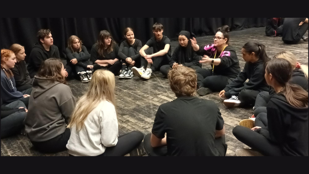 Performing arts students sit in a circle with comedian Allyson Smith 